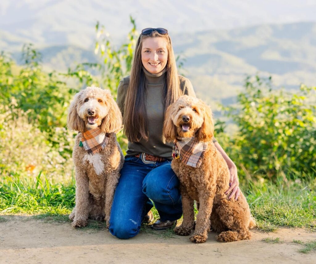 Woman smiling outside next to her 2 dogs