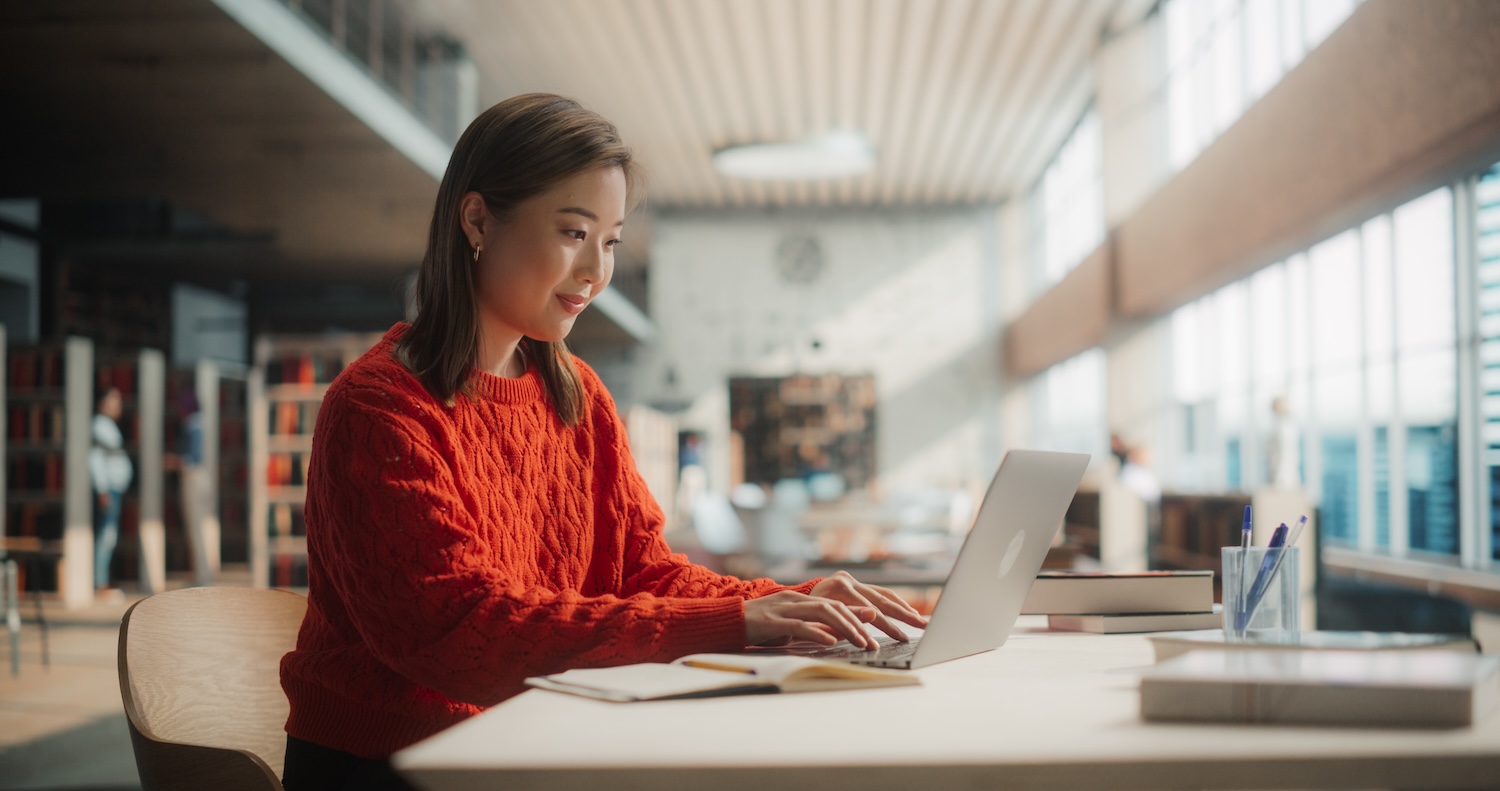 Asian student smiling at computer