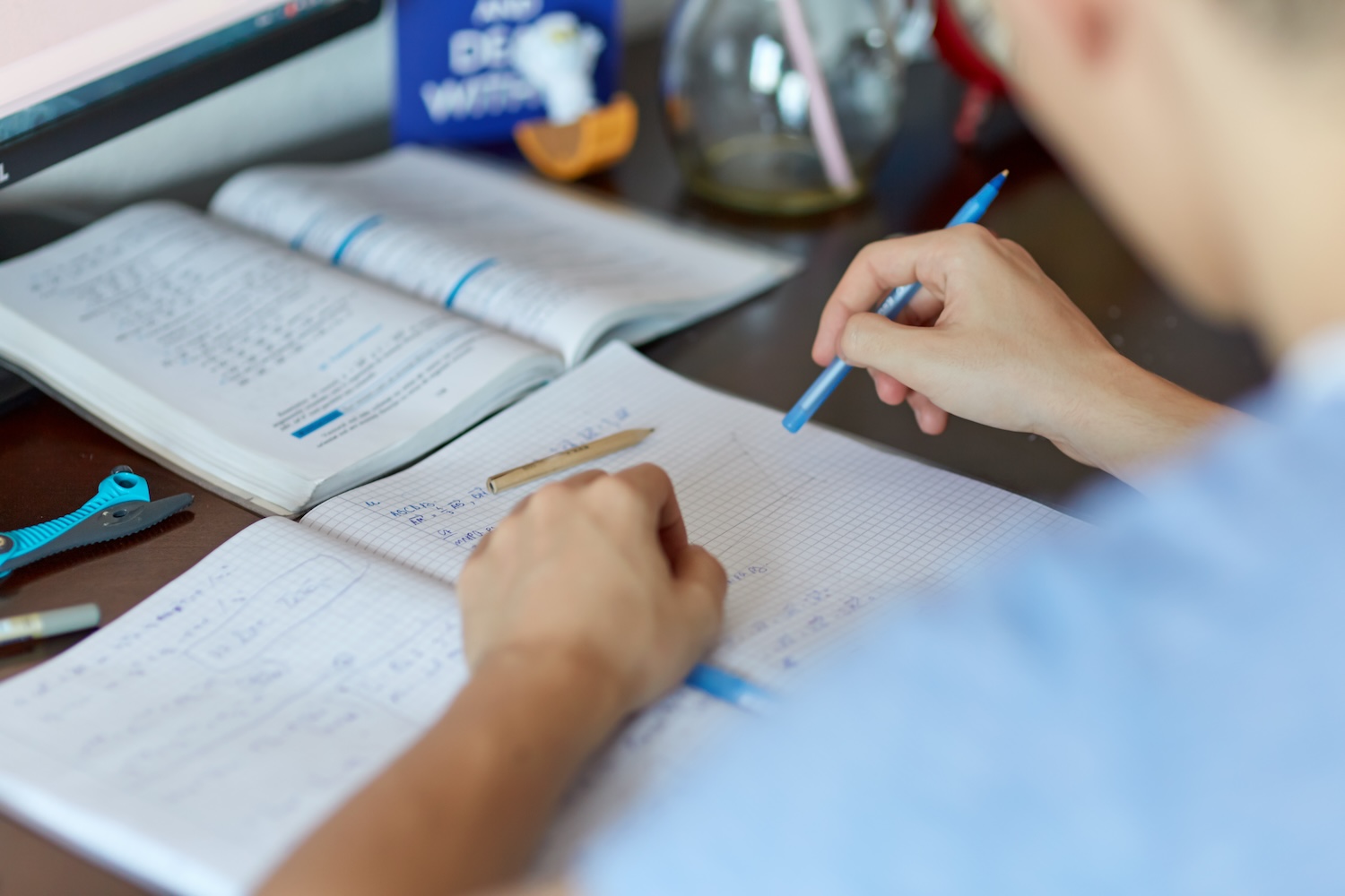 Student completing math equation on grid paper holding pen