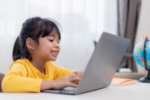 Child wearing yellow shirt working at laptop