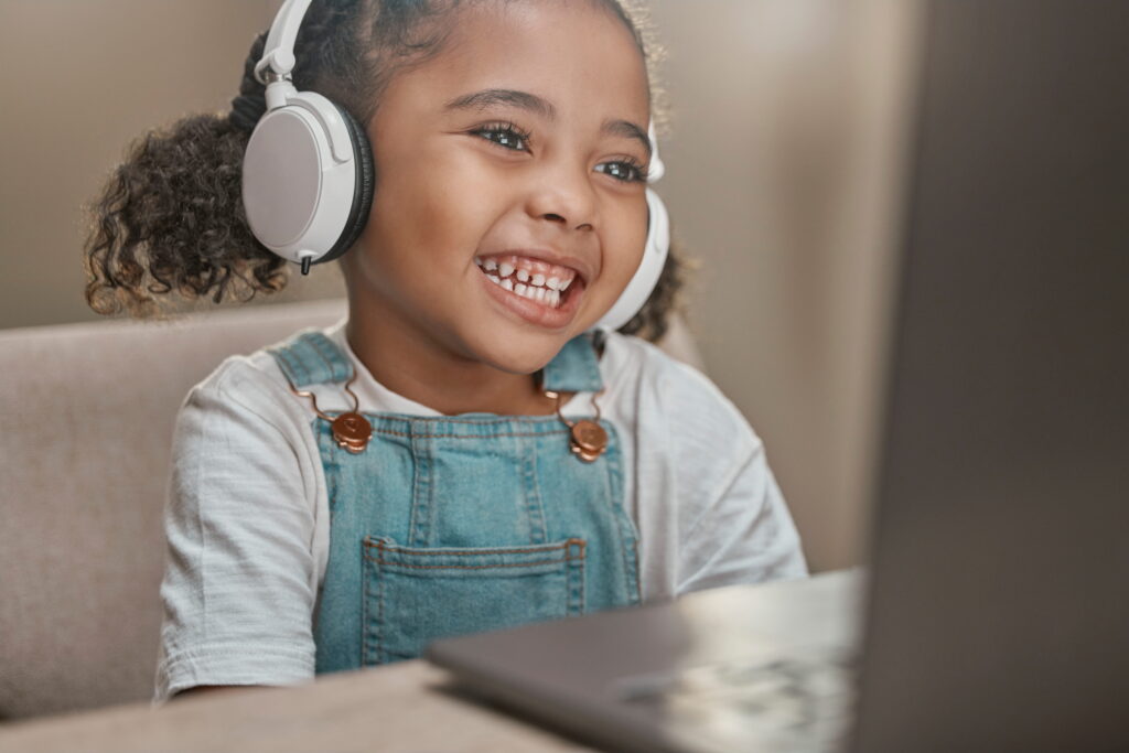 child wearing headphones, smiling at computer screen