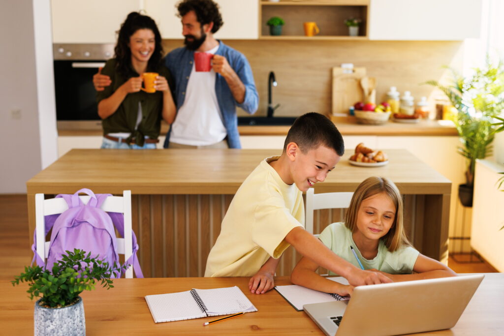 online students working at kitchen table on laptop