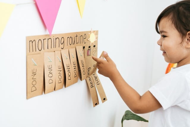 Young child completing a chore chart while balancing online school.